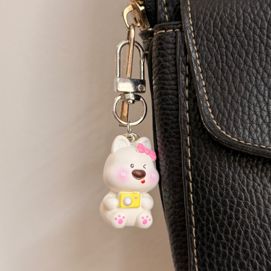 Say Cheese, a white puppy with a pink bow and a yellow camera.