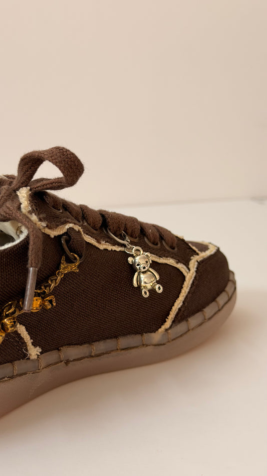 Silver Teddy Shoe Charm, polished silver teddy bear charm on the laces of a brown canvas sneaker