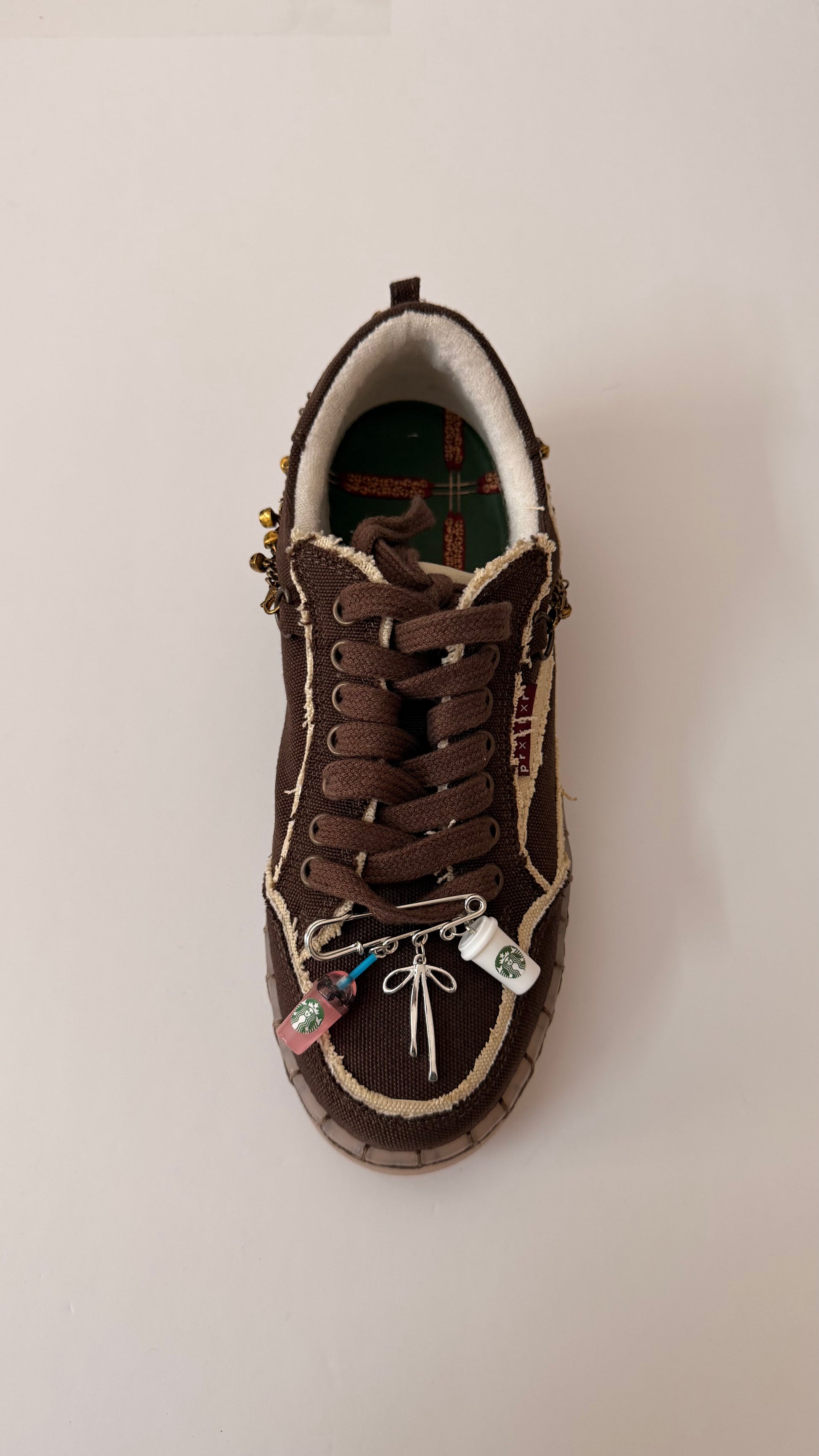 Sip Era, brooch pin fastened to the laces of a brown canvas sneaker