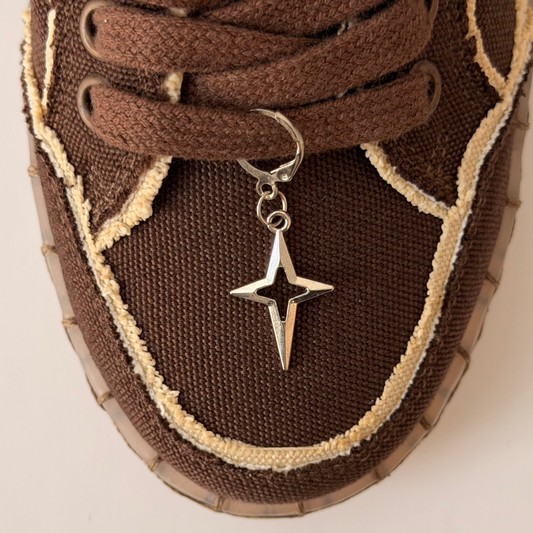 Star Bling Shoe Charm, silver four-point star charm with a cut-out centre on the laces of a brown canvas sneaker