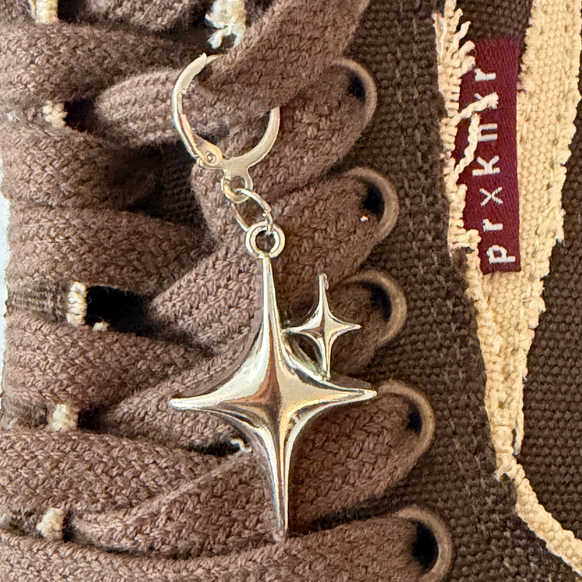 Starstruck Shoe Charm, puffy silver sparkle star charm on the laces of a brown canvas sneaker
