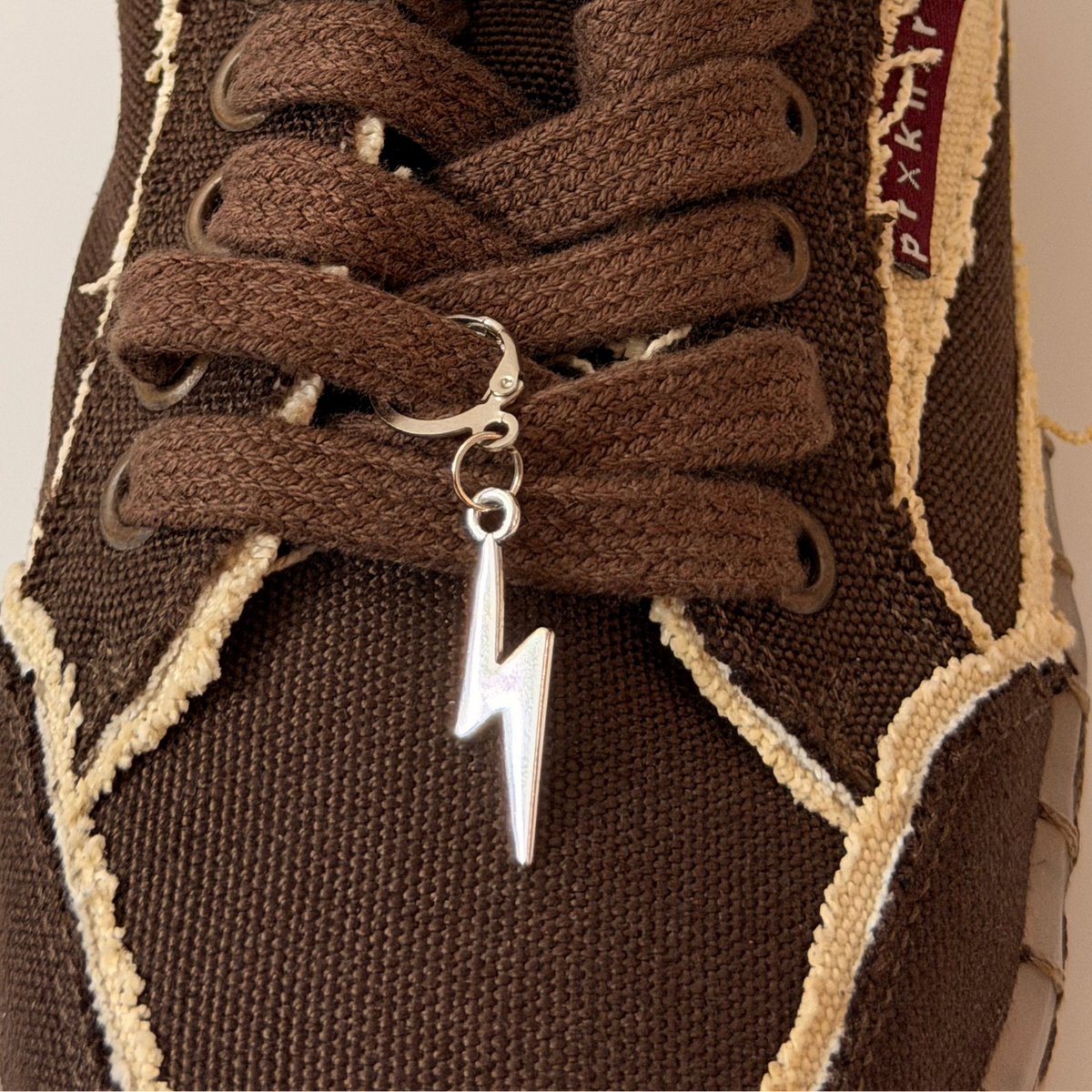 Thunderbolt Shoe Charm, silver lightning bolt charm on the laces of a brown canvas sneaker