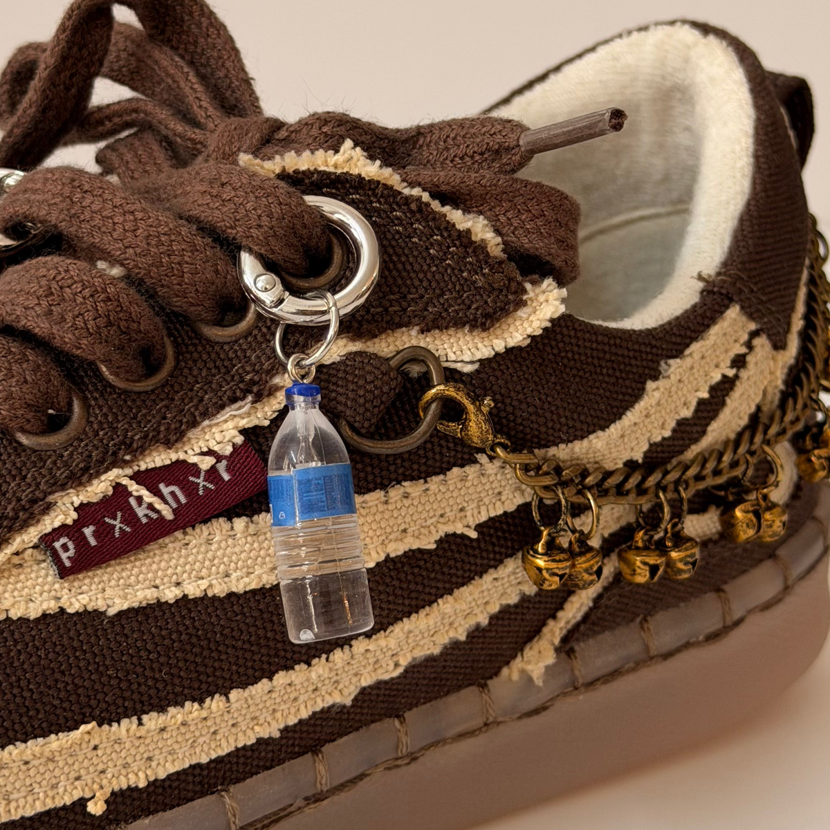 Water Bottle Shoe Charm, mini water bottle charm with a blue cap on the laces of a brown canvas sneaker