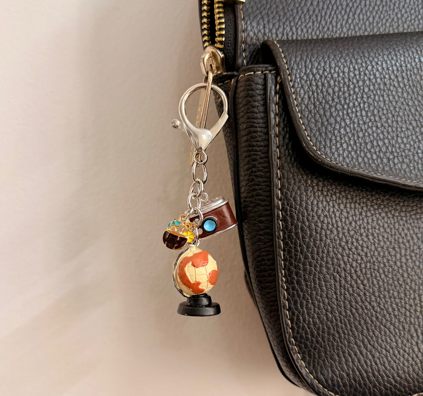 Where to Next?, a globe on a stand with a vintage camera clipped to a black leather handbag zip.