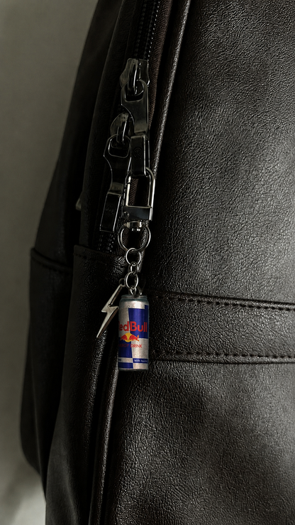 Red Bull can bag charm with silver lightning bolt on a black backpack zipper